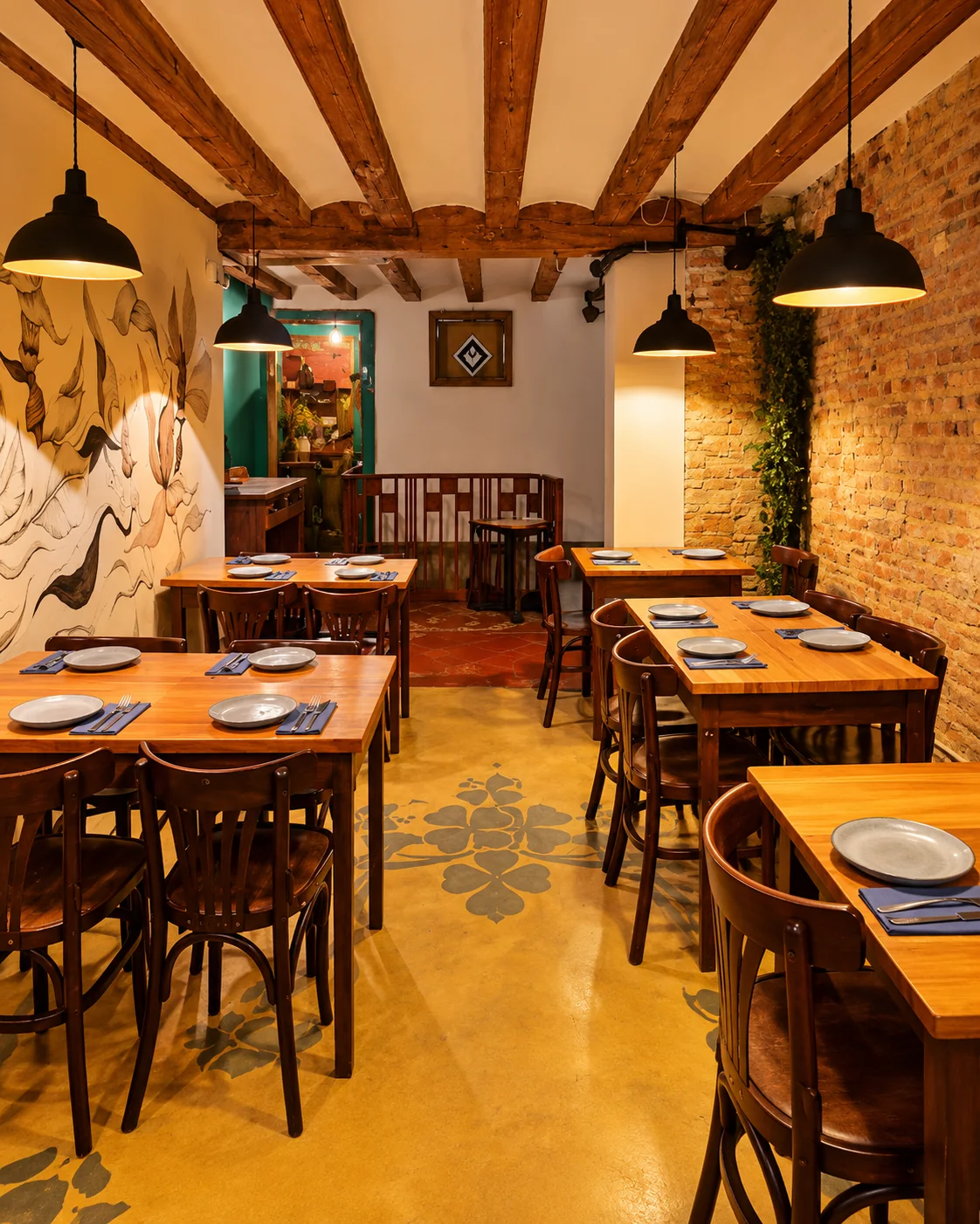 Comedor bajo vigas de madera, con el mural botánico a un lado y ladrillo visto al otro